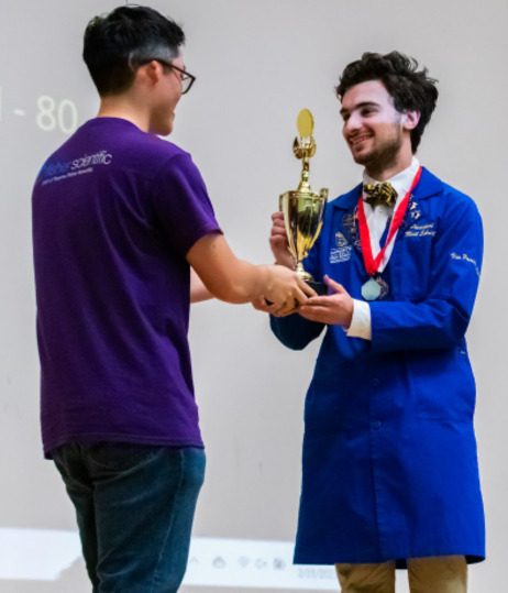 A Northwestern Science Olympiad volunteer presents a trophy to a competitor.
