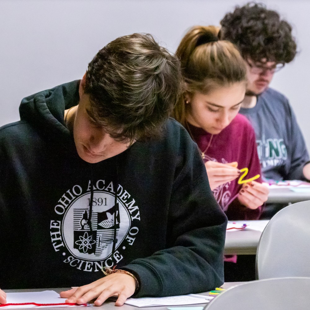 Students complete written tests during a Science Olympiad event.